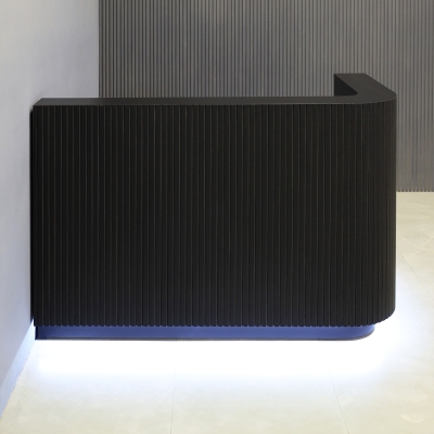 60-inch Nola L-Shape Custom Reception Desk with the l-panel on the right side. The main desk is covered in black traceless tambour, the workspace and toe-kick in black matte laminate, and comes with warm white LED.