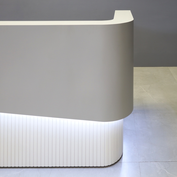 60-inch Nola Curved Reception Desk in folkstone gray matte laminate counter & inside desk, white tambour outside desk, and warm white LED.