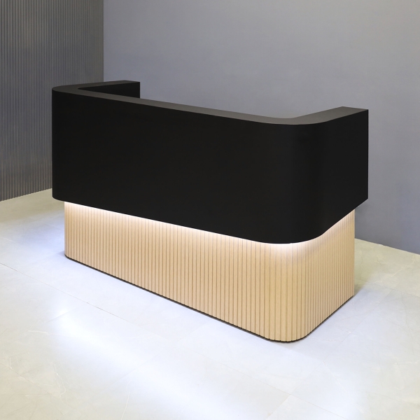 72-inch Nola Curved Custom Reception Desk in black traceless laminate counter, maple tambour bottom, and warm white LED.